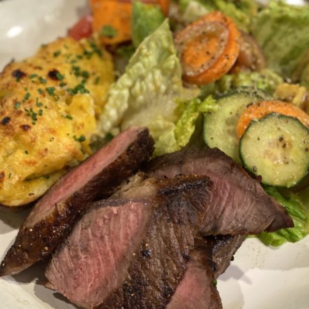 Medium Rare Steak, Twice Baked Potato, and a Garden Salad arranged on a plate.